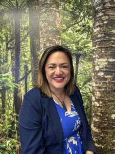 Raukahawai O'Connor a Māori woman is smiling in front of a backdrop of native New Zealand forest